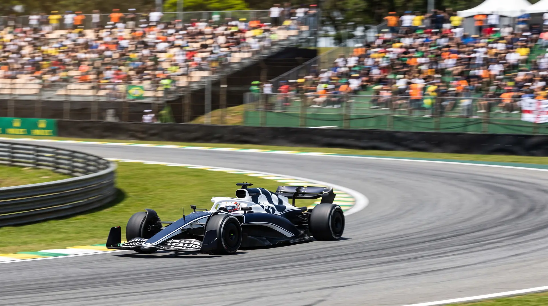 Formula 1 race car on track during a Grand Prix in Brazil, with grandstands full of fans in the background